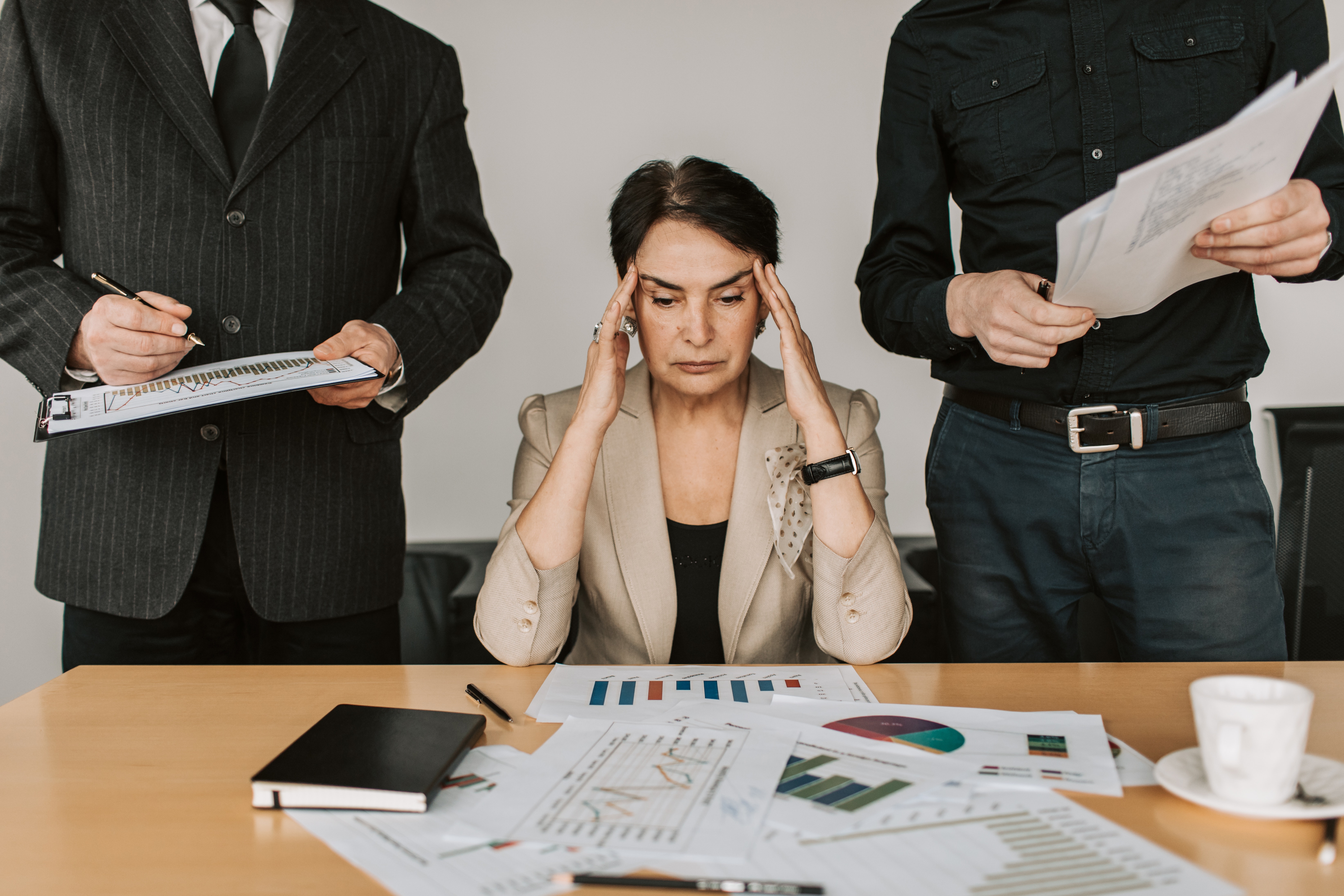 Corporate woman between two men expressing frustration amongst paperwork